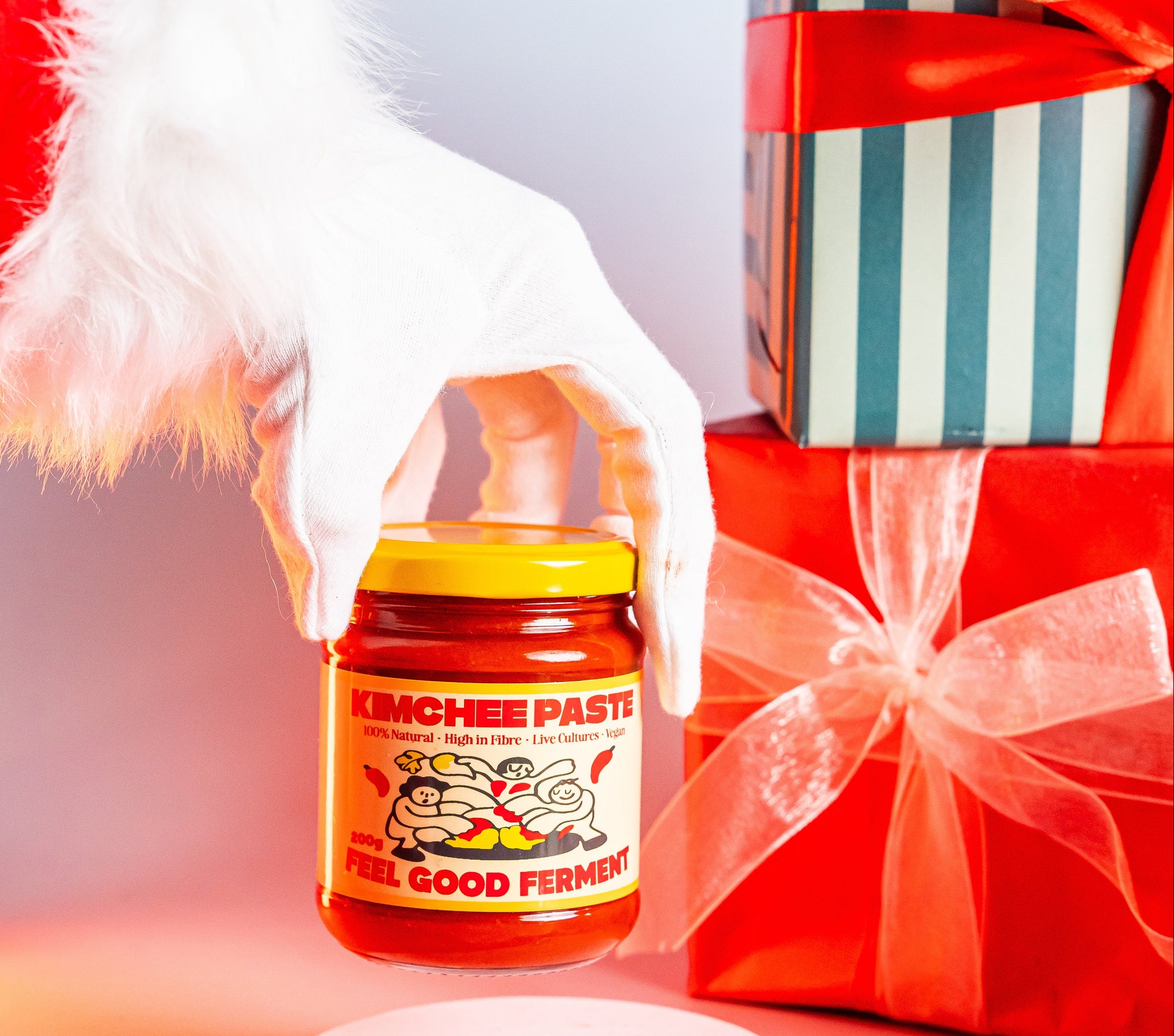 Hand holding a jar of kimchee paste with a gift box in the background